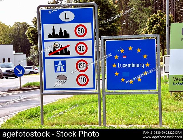 08 August 2021, Luxembourg, Wemperhardt: Border sign Luxembourg, bordered by Europe stars on a blue background, on the German-Luxembourg border and sign on the...