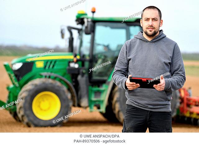Landwirt Stefan Bohlender steht am 23.03.2017 in Steinweiler (Rheinland-Pfalz) mit einem Tablet vor seinem Traktor, der mit Hilfe des Globalen...