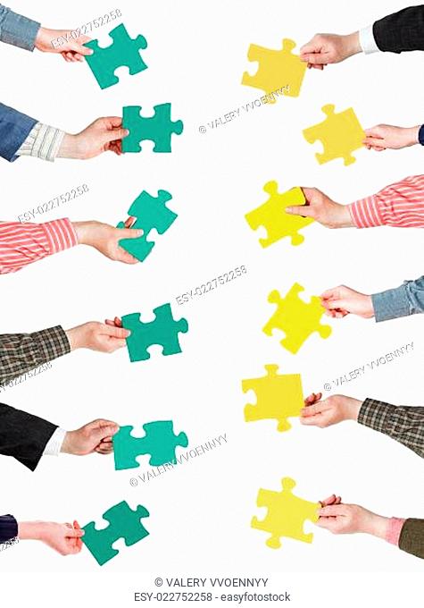 green and yellow puzzle pieces in people hands