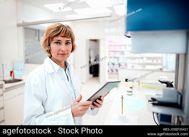 Female professional holding digital tablet while standing at laboratory