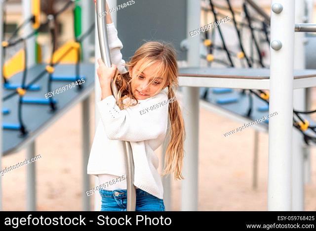 Pretty little girl playing on children playground, ready to slide fire pole