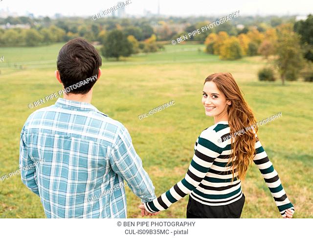 Rear view of couple holding hands in field