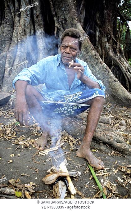 Portrait of an elderly man smoking a cigarette at the foot of a banyan tree, Sulphur Bay Village, Ipekel Ipeukel, Tanna Island, Vanuatu