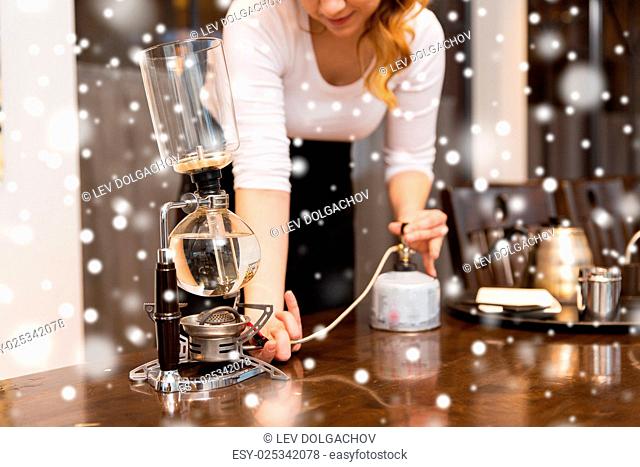 equipment, coffee shop, people and technology concept - close up of woman with butane gas burner heating water in siphon coffeemaker at cafe bar or restaurant...