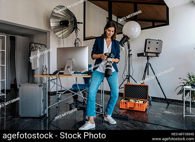 Photographer holding camera standing in studio