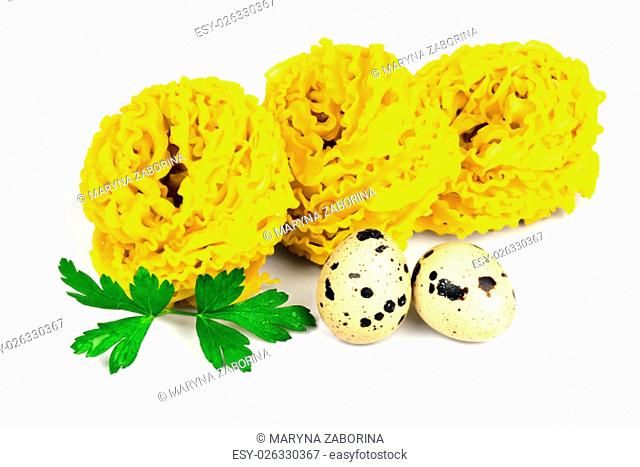 Italian raw curly fettuccine pasta with two quail eggs and parsley isolated on white background