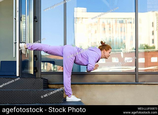 Woman exercising warrior position on staircase in front of glass wall