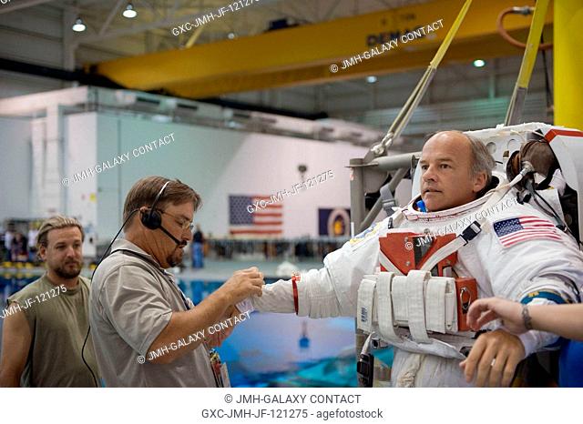 Astronaut Jeffrey Williams, Expedition 21 flight engineer and Expedition 22 commander, gets help in the donning of a training version of his Extravehicular...