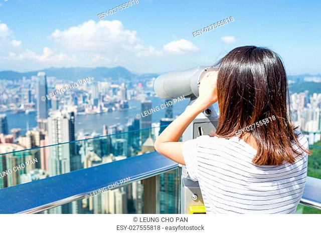 Tourist using binocular looking though Hong Kong cityscape