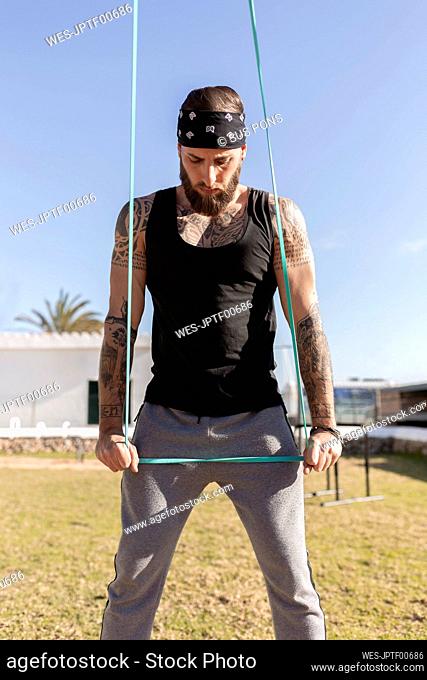 Male athlete pulling resistance band while exercising in park