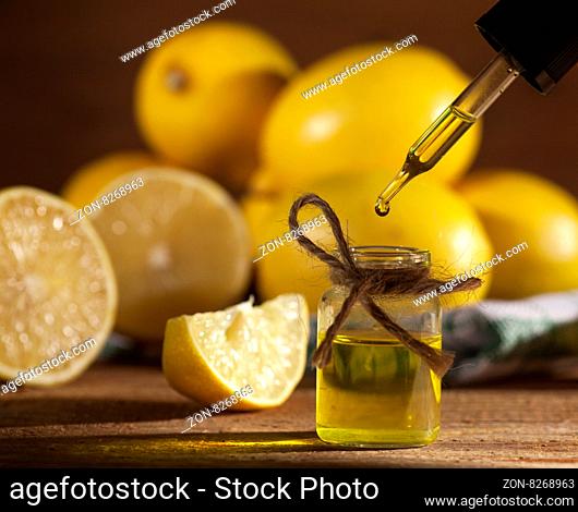 Lemon essential oil and lemon fruits on wooden background