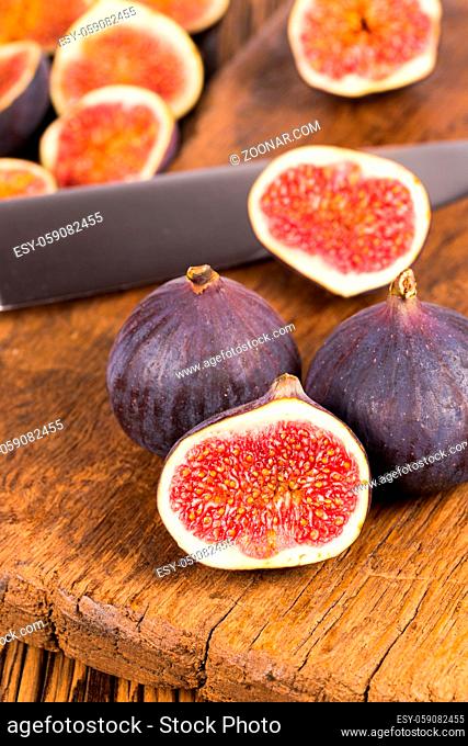 Group of whole and sliced ripe, delicious and sweets figs with a kitchen knife on a old rustic wooden cutting board