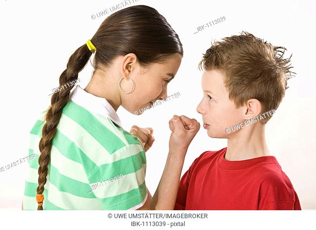 Small boy and a bigger girl threatening each other with their fists
