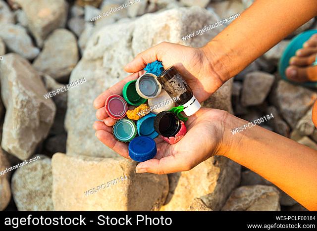 Hands of woman bottle caps and garbage at beach