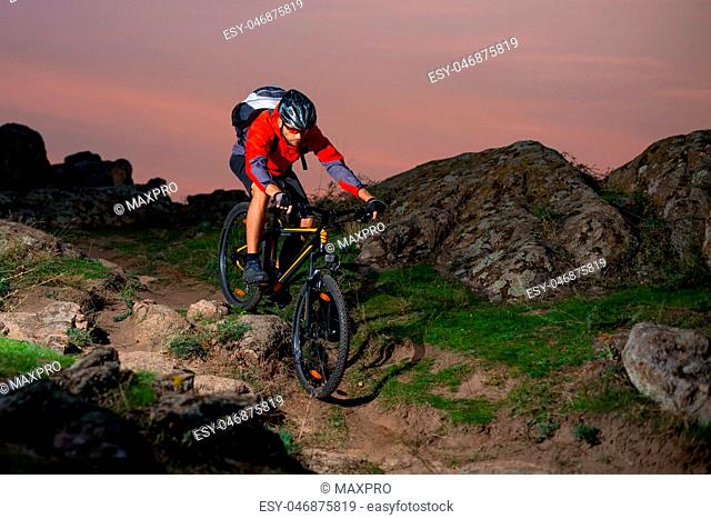 Cyclist in Red Riding the Bike on Autumn Rocky Trail at Sunset. Extreme Sport and Enduro Biking Concept