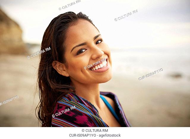 Portrait of smiling young woman wrapped in towel on beach, San Diego, California, USA