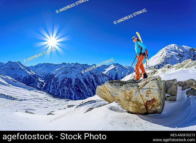 Austria, Tyrol, Lone female skier admiring snowcapped landscape in Zillertal Alps