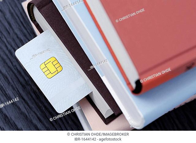 Smart card in a stack of books, symbolic image for an educational smart card