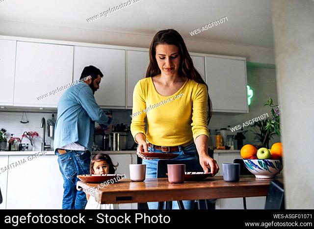 Woman cleaning table while family in background at home