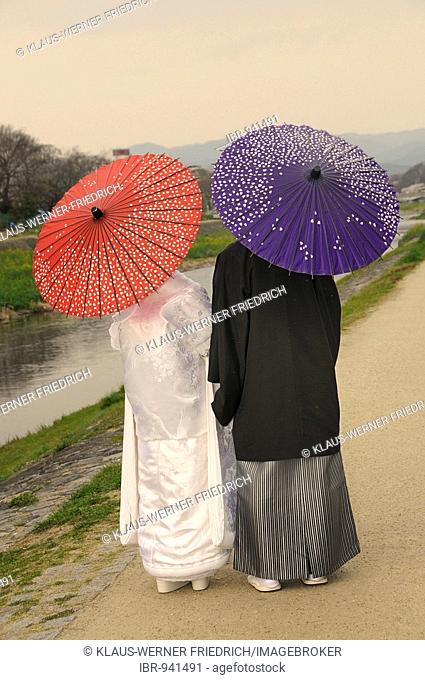 Traditional Japanese wedding couple with traditional paper parasols on the Kamigamo River, Kyoto, Japan, Asia