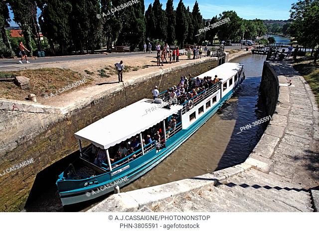 France, Southern France, Canal du Midi. Fonseranes lock near Beziers with a touristic boat going through the round lock. White and blue boat view from above to...