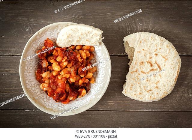 Dish of baked beans with tomato sauce and flat bread