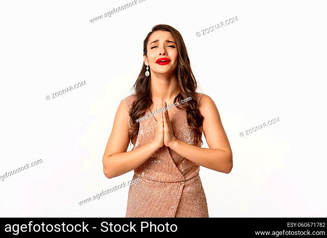 Celebration and party concept. Desperate woman in glamour dress begging for something, need help and holding hands in pray, crying and pleading you
