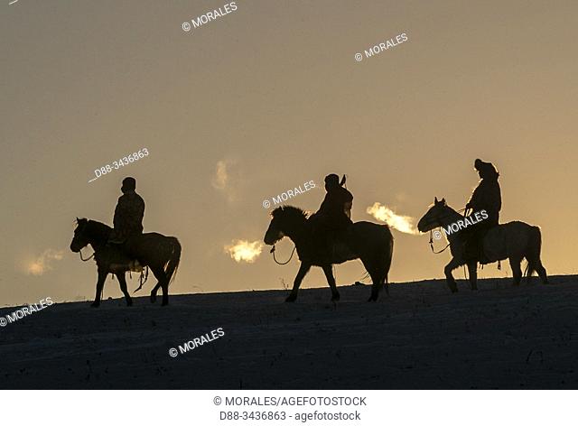 China, Inner Mongolia, Hebei Province, Zhangjiakou, Bashang Grassland, three Mongolian horsemen on a horse running in a meadow covered by snow