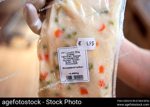21 April 2020, Brandenburg, Klaistow: In the farm shop, saleswoman Iwona shows a packet of chicken fricassee pre-cooked in the sous-vide method