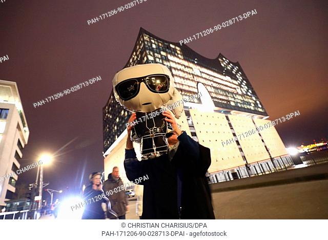 A woman with a Lagerfeld mask stands in front of the Elbe Philharmonic Hall in Hamburg, Germany, 06 December 2017. Lagerfeld celebrated his premiere with an...