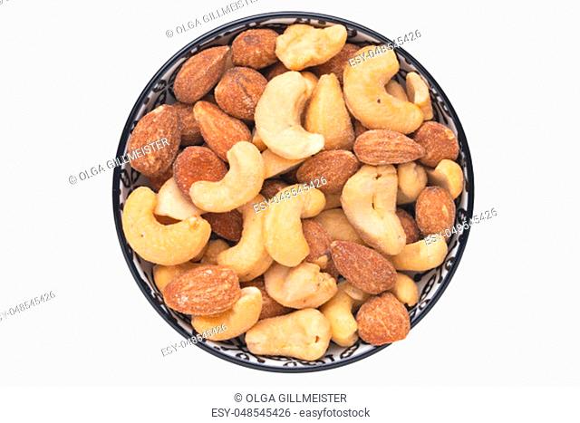 Nuts background. Close-up of roasted and salted almonds and cashew nuts in a ceramic bowl isolated on a white background. Gourmet nut mix with almonds