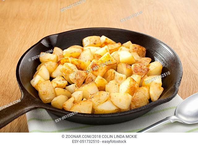 A small cast iron skillet or frying pan filled with home fries or saute potatoes