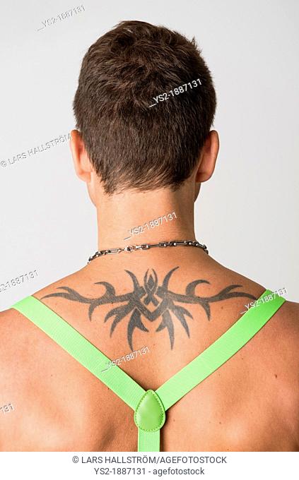 Rear view of shirtless man with tattoo wearing suspenders