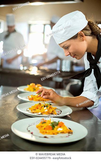 Female chef garnishing plate of food