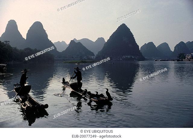 Cormorant fishermen on stretch of river in the Guilin area with limestone peaks behind