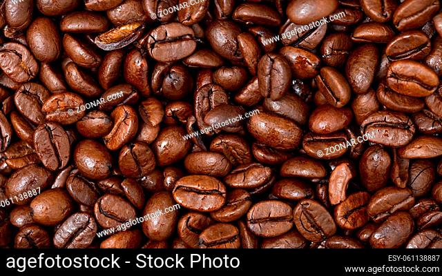 Fullframe shot of fresh roastend coffee beans zoom in. Aromatic brown textured seeds on background from close up. Black energy structured grain on backdrop