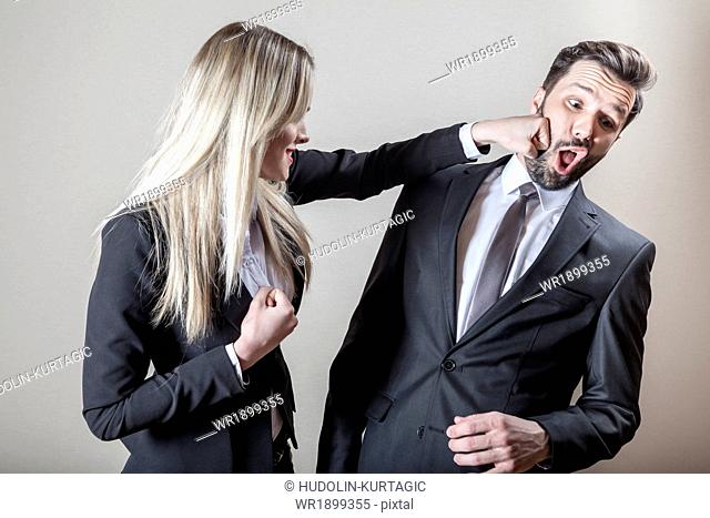 Businesswoman hitting businessman with fist