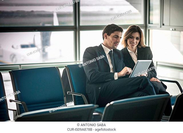 Businesspeople using digital tablet in airport departure lounge