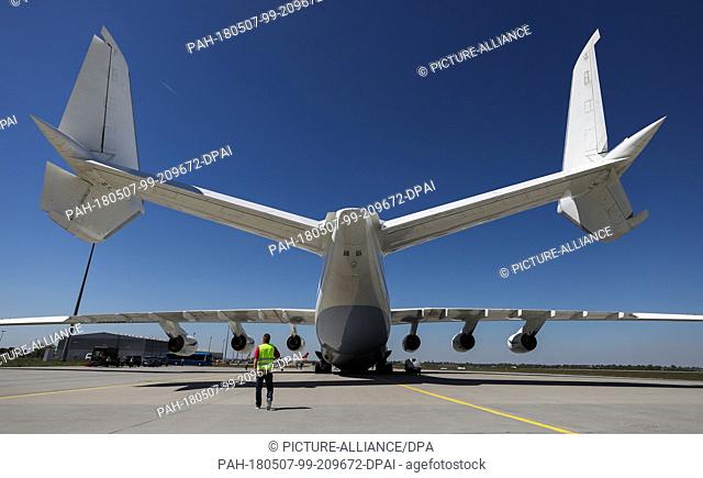 dpatop - 07 May 2018, Germany, Schkeuditz, Leipzig-Halle Airport: A man walking under an Anotonov 225. The 84 -meter long