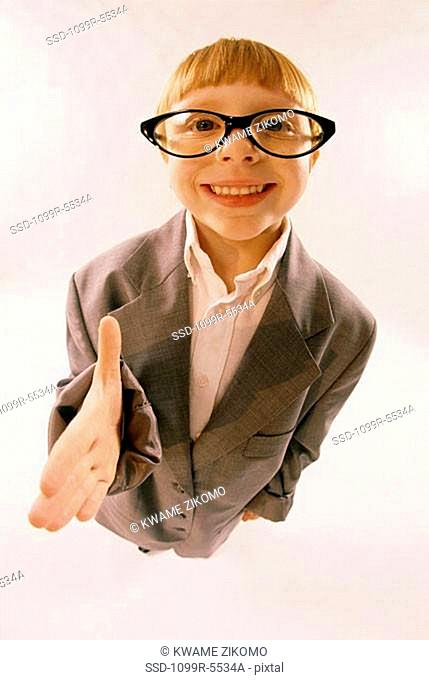 Portrait of a young boy dressed as businessman holding his hand out smiling