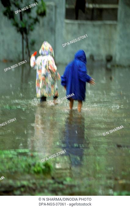children walking in monsoon water on road ; kutch ; gujarat ; india MR.NO.342