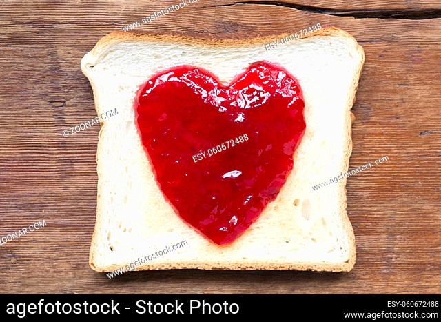 fried toast with red jam in shape oh heart on vintage wood