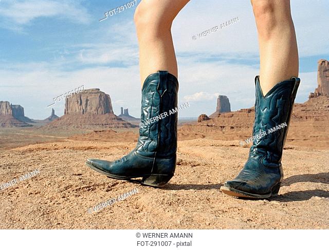 Woman standing in desert wearing cowboy boots