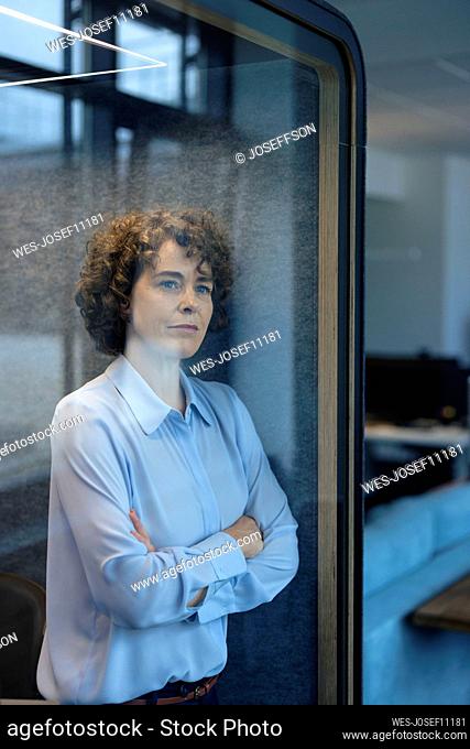 Businesswoman standing with arms crossed in soundproof cabin