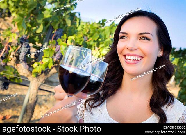 Pretty Mixed Race Young Adult Woman Enjoying A Glass of Wine in the Vineyard with Friends