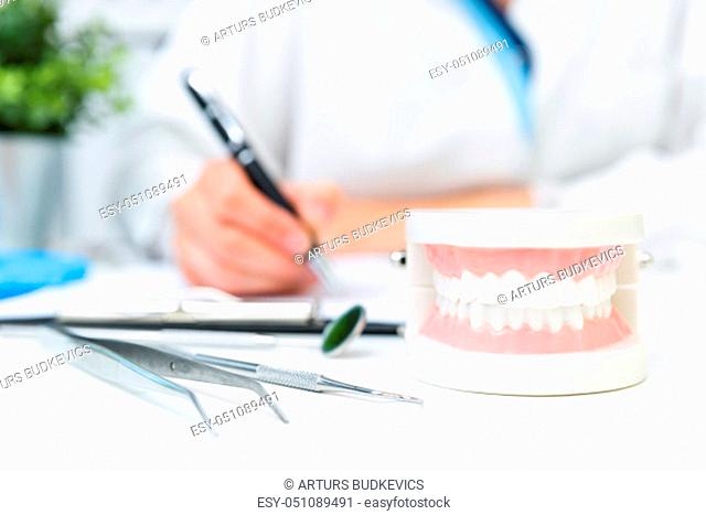 Female dentist holding professional stomatology tool and pointing at the teeth model. Dental hygiene and health concept