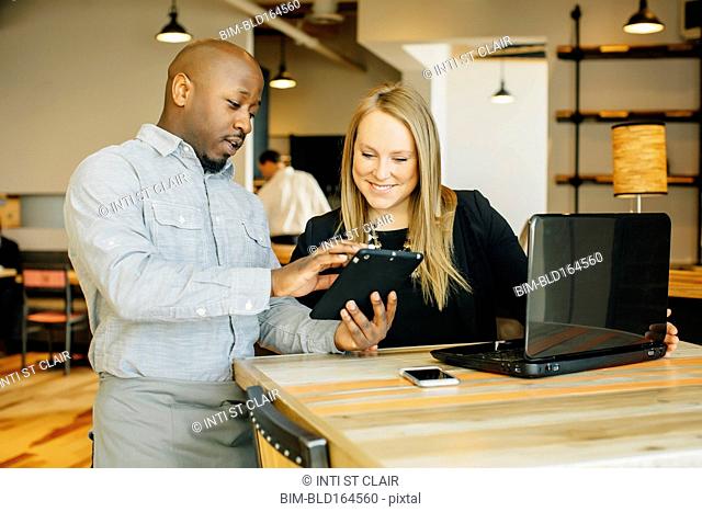 Barista and businesswoman using technology in cafe
