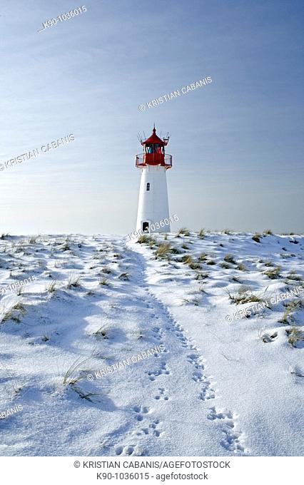 Lighthouse List West, seen from a low perspective, on snow covered dunes showing tracks of a rabbit leading to the lighthouse