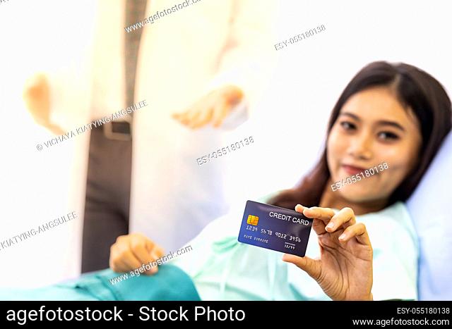 Portrait of Young adult female Patient with credit card in bed of hospital ward