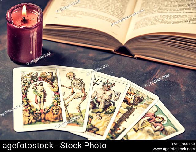 Tarot cards with candlelight and book on the darkness background, Halloween and future reading concept